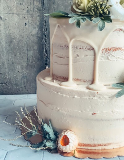 White cake with white drip icing against a pale blue wall
