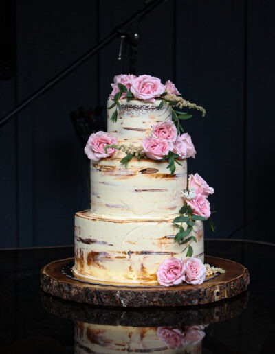 Semi-naked wedding cake with pink and white roses, made by Epiphany Cakes in Nelson, BC