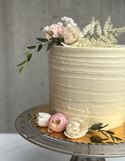 Single-tier wedding cake with textured buttercream and fresh greenery, made in Nelson, BC