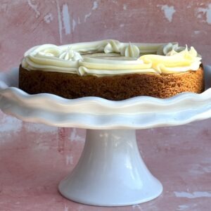 Carrot cake cheesecake with cream cheese frosting on a white cake stand