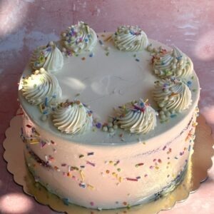 Birthday cake with pastel blue and pink buttercream, sprinkles and piped rosettes