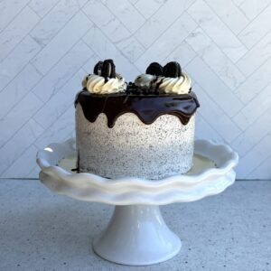 Cookies and cream cake with chocolate drip on a white cake stand