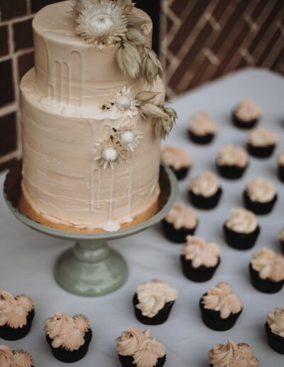 Tiered white wedding cake with matching mini cupcakes