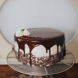 Vanilla buttercream cake with a chocolate ganache drip on a cake stand