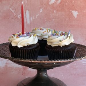 Chocolate cupcakes topped with buttercream and a lit candle, gluten-free available at Epiphany Cakes in Nelson, BC