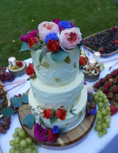 Pale blue wedding cake with fresh flowers on a berry dessert table, made by Epiphany Cakes in Nelson, BC