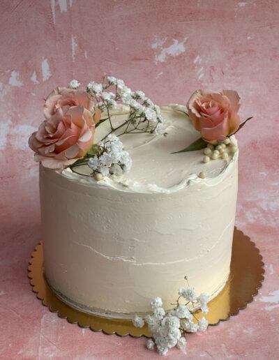 Cheesecake wedding cake topped with pink roses and greenery