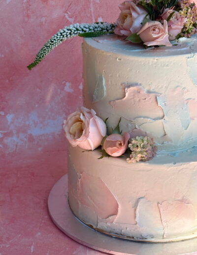 Wedding cake with soft pink and blue watercolour frosting and sugar flowers